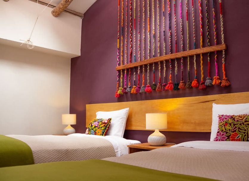Casa de La Chola Ollantaytambo twin beds with colorful woven wall decor and bedside lamps