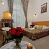 Unikat Guest Rooms in Krakow: cozy guest room with double bed, floral lamp, and red roses on a table