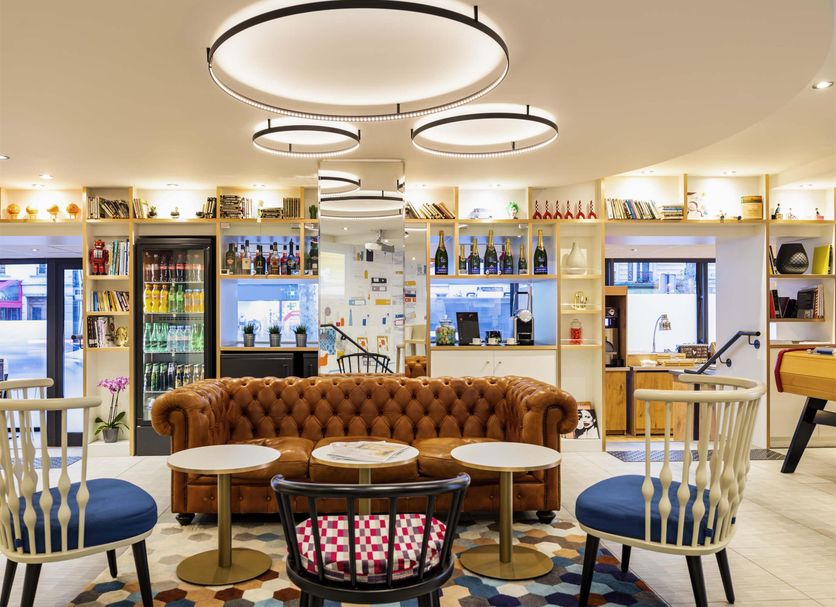 ibis Paris Gare de Lyon Diderot 12ème bar lounge in Paris with tufted sofa, round tables and lit shelves