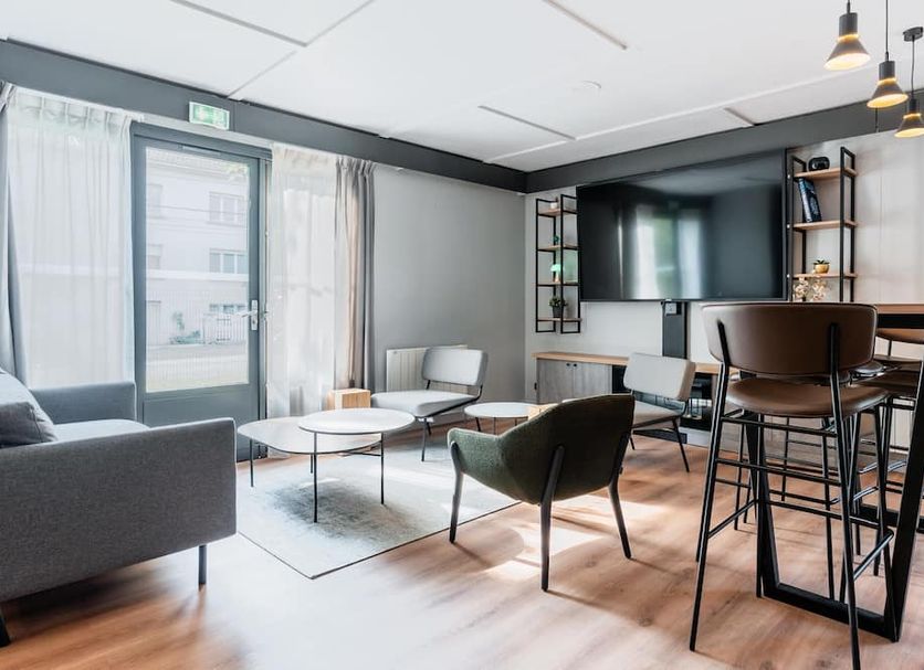 Campanile Vannes in Vannes: modern lounge with seating, bar stools and large TV near a glass door