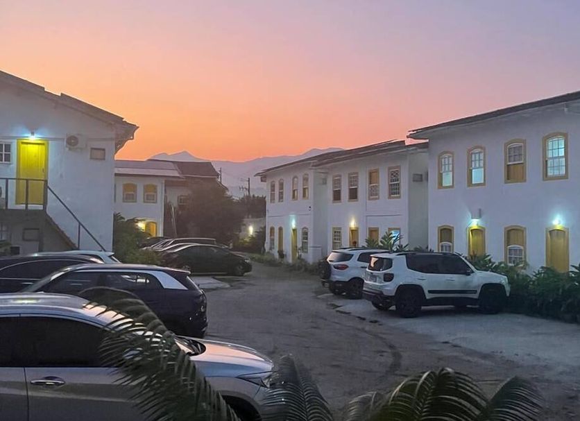Pousada Fortaleza in Paraty with white guest buildings and parked cars at sunset