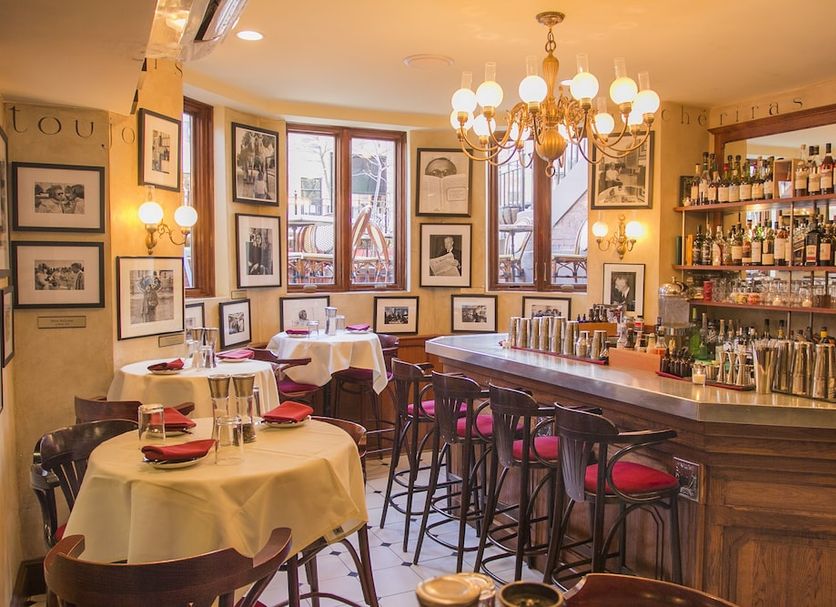 Newbury Guest House Boston bar and dining room with tables, stools, framed art and chandelier