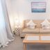 Inn On Peaks Island on Peaks Island: cozy guest room with beige sofa, coffee table, curtains and framed seascape.