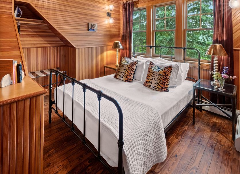 Hotel Mountain Brook, Tannersville: cozy wood-paneled bedroom with black metal bed, large windows, and pendant light.