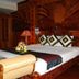 Majestic Oriental Hotel in Siem Reap bedroom with carved wooden bed and floral arrangement