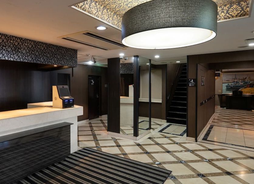 Apa Hotel Tokyo Ojima lobby with check-in counter, mirrored columns and patterned tile floor in Tokyo