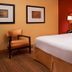 Courtyard by Marriott Louisville East guest room with king bed, armchair, and bedside lamp in Louisville