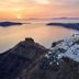 Sunset view over Santorini Mansion at Imerovigli, with white hillside buildings and sea cliffs.