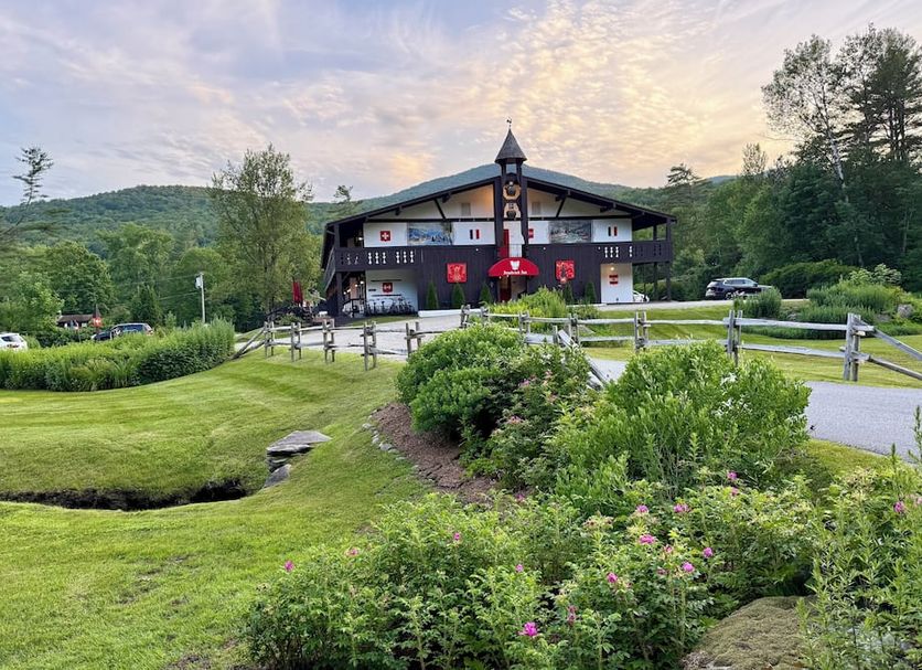Innsbruck Inn at Stowe exterior with landscaped lawn and mountain backdrop in Stowe