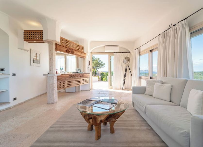 Hotel Balocco in Porto Cervo: bright suite with sofa, glass coffee table, sea view and terrace doors