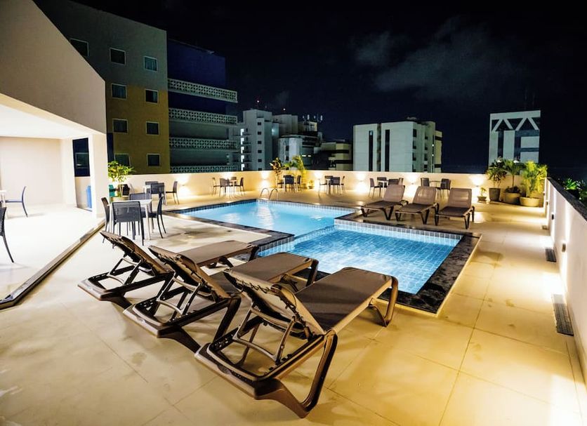 El Aram Beach Express rooftop pool deck in Maceió with lounge chairs and city views at night