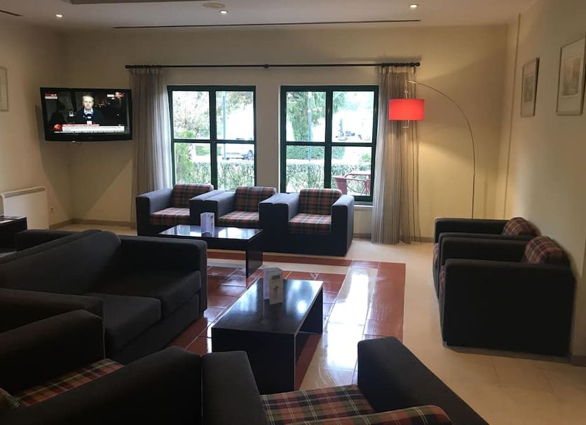 Viseu Garden Hotel lounge in Viseu with sofas, coffee table, large windows and a red floor lamp