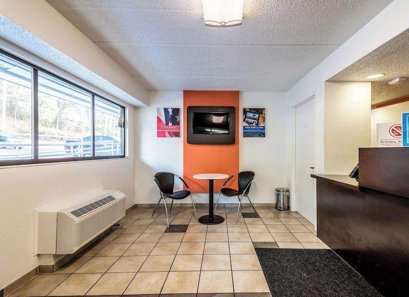 Motel 6 Birmingham lobby with check-in desk, seating area, wall TV, and large front windows