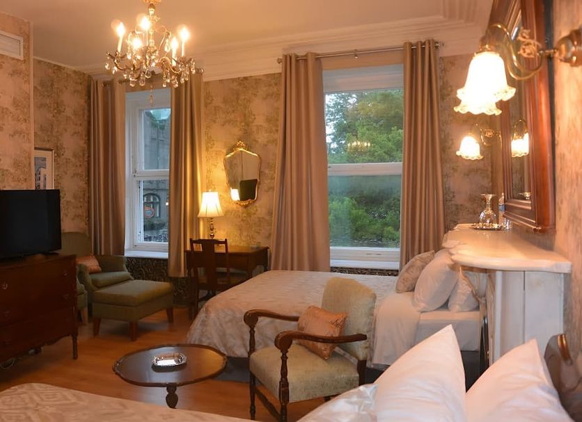 Manoir Sainte Genevieve room in Québec City with bed, chandelier, windows, and seating area