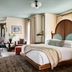 Zelda Dearest in Asheville, bedroom with arched wood headboard, teal chairs, and dining area
