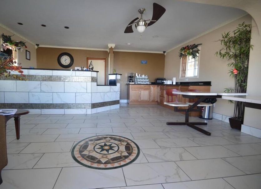 Executive Inn Snyder lobby with tiled floor, front desk, seating area and ceiling fan
