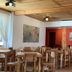 Hosteria Posta de los Colonos dining room with wooden tables, red walls, and ceiling lights in Villa La Angostura