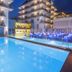 Hotel Alhambra in Santa Susanna with a lit outdoor pool and balcony-lined hotel buildings at dusk