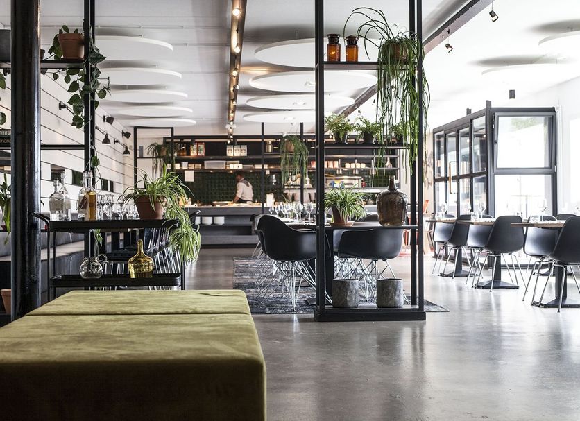 Hotel Mooirivier in Dalfsen lobby lounge with bar, black chairs, large windows, and indoor plants