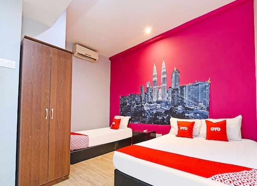 Hotel O Elwarda Klcity Kuala Lumpur room with two beds, wardrobe and bright pink city mural wall