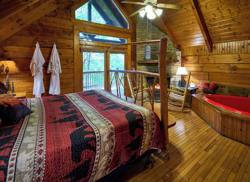 A Cabin In The Woods in Pigeon Forge: rustic cabin bedroom with jacuzzi tub and mountain-view windows