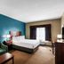 The Hotel Saratoga guest room in Saratoga Springs with king bed, teal accent wall, sofa, and window seating