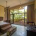 Triose Boutique Hotel Lonavala room with bed, TV, and sliding glass doors to a tropical patio.