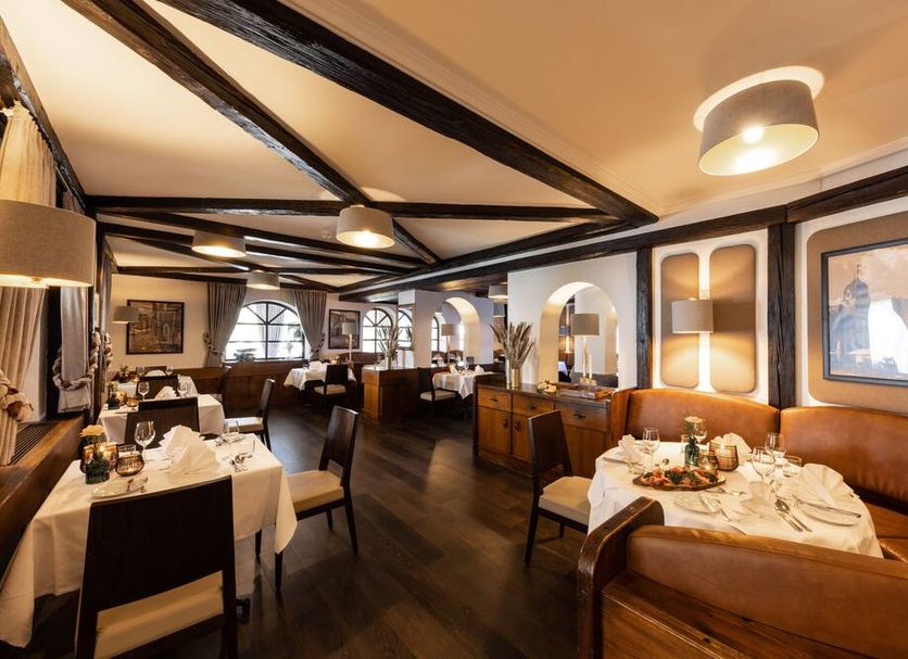 Tanneck in Bad Woerishofen dining room with set tables, leather banquette seating and arched windows