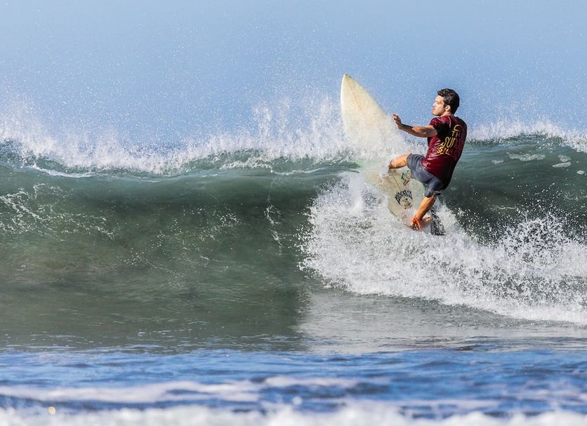 The Sunset Shack Nosara: surfer riding a wave in the ocean