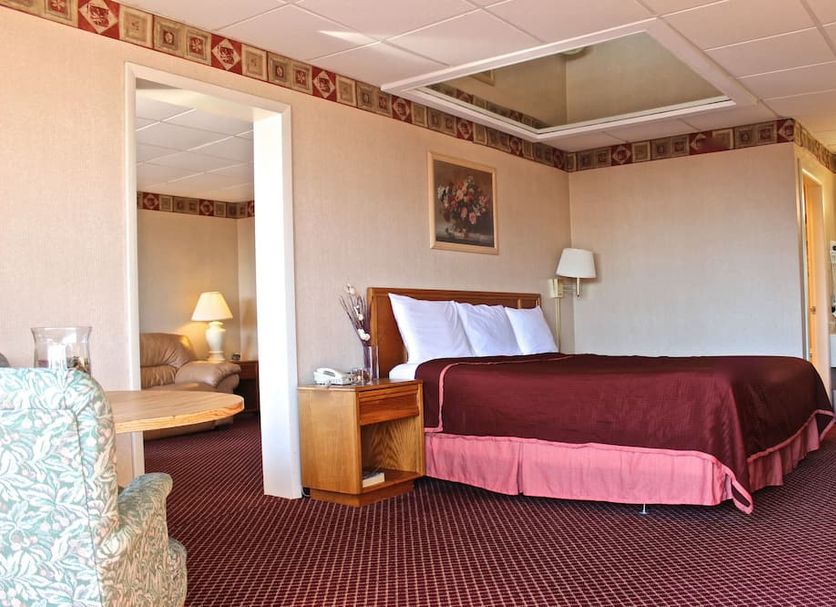 Regency Inn Richmond guest room with king bed, chair, and bathroom vanity in Richmond