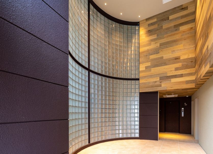 The Onefive Marine Fukuoka lobby with curved glass block wall and wood-paneled accents in Fukuoka