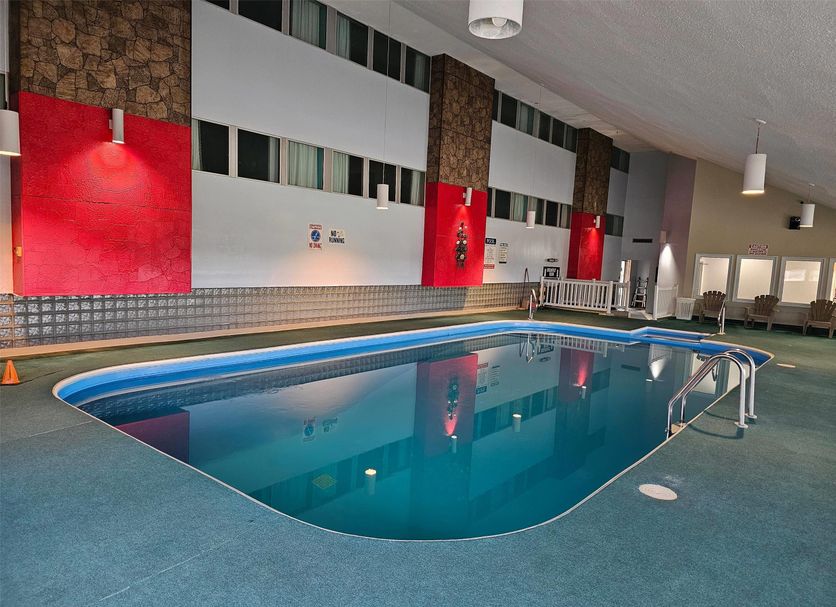 Indoor pool at Howard Johnson by Wyndham Woodstock NB in Woodstock with ladder and lounge chairs