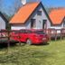 Grindsted Aktiv Camping in Grindsted with red-roofed cabins and a red car parked beside a wooden deck