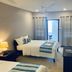 La Isla Resort in Caye Caulker guest room with two beds, balcony door, and ceiling fan