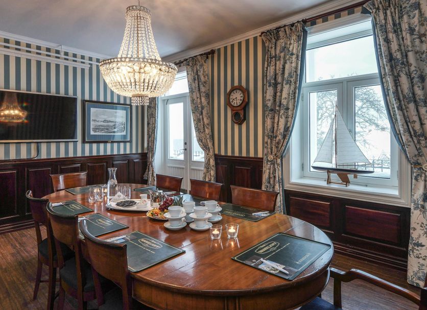 Hotel Wassilioff in Stavern dining room with chandelier, striped walls, and a large oval table