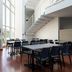 Kyriad Eco Lille Sud - Noyelles Godault breakfast area with tables, chairs and staircase in bright atrium