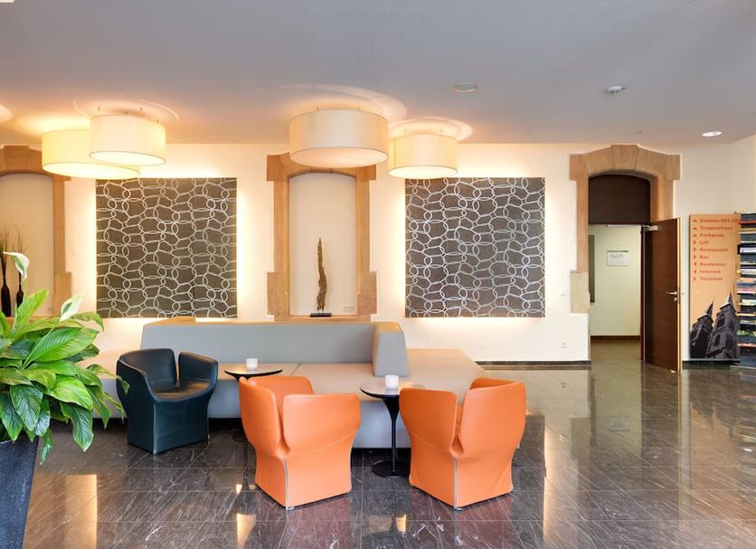Novina Hotel Tillypark in Nuremberg lobby seating area with orange and black chairs and stone accent walls