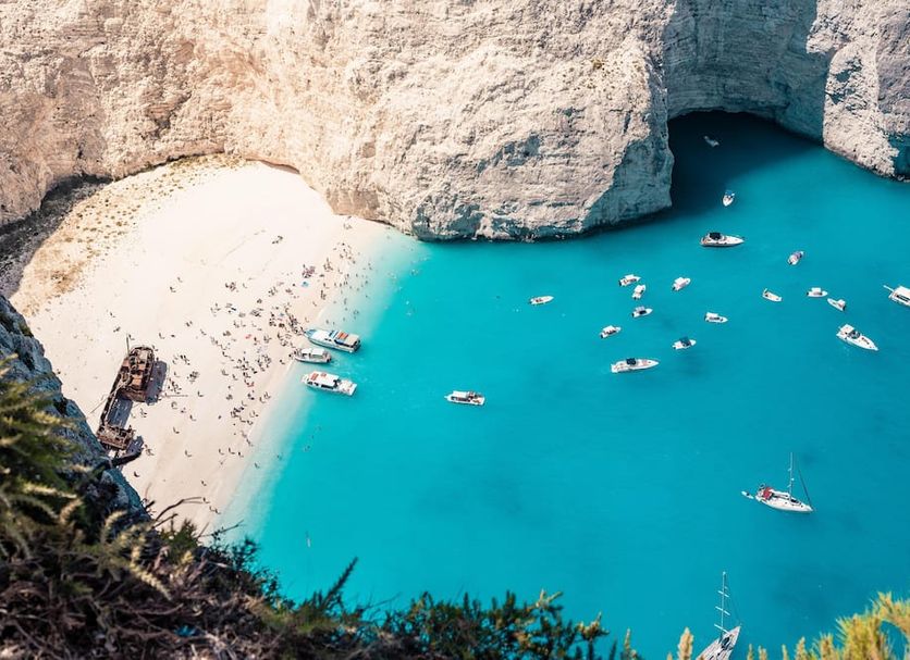 Atlantica Eleon Grand Resort in Tragaki overlooking a turquoise cove with sandy beach and boats