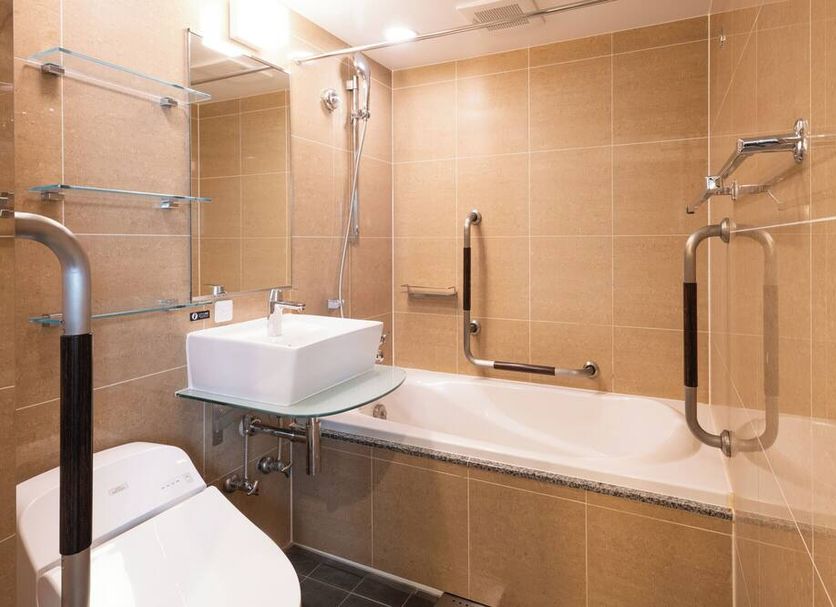 Apa Hotel Kanda Ekimae bathroom in Tokyo with bathtub, sink, grab bars and shower