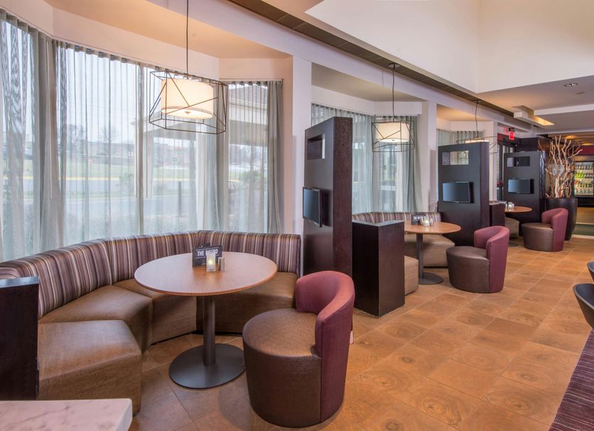 Courtyard by Marriott Fairfax Fair Oaks lounge seating area with round tables and booths in Fairfax