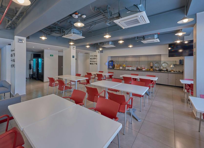 City Express Junior by Marriott Guadalajara Periférico Sur breakfast room with red chairs and dining tables