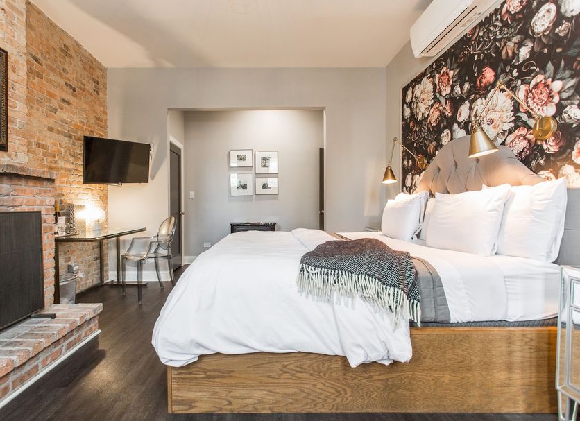 The Wicker Park Inn Chicago guest room with king bed, brick fireplace, and floral accent wall