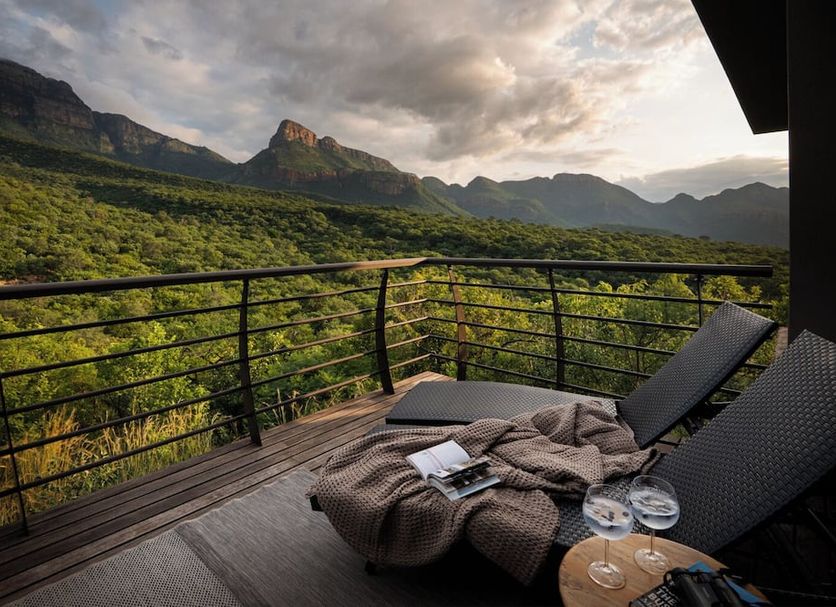 Umvangati House in Hoedspruit: balcony with lounge chairs and mountain valley views at sunset