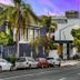 Balboa Park Hotel in San Diego with palm-lined street and city buildings at sunset