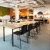 Conscious Hotel The Tire Station Amsterdam meeting space with tables, black chairs and bar area