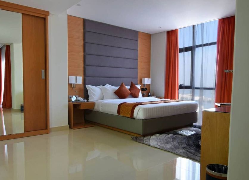 Meshal Hotel & Spa in Manama guest room with king bed, floor-to-ceiling window, and mirrored wardrobe