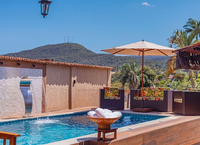 Jardim Do Eden Piri in Pirenópolis with a pool, umbrella-shaded seating, and mountain views