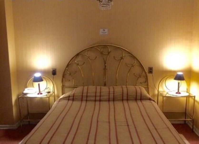 Hotel Foresta Santiago guest room with double bed, bedside lamps and warm yellow walls