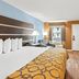 Baymont by Wyndham Forest City guest room with two beds, TV, seating area, and window view