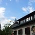 Haus Wartenberg in Salzburg exterior with mural, shuttered windows and blue sky